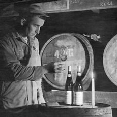 A black and white image of Richard Sommer looking at a glass of wine in the barrel room