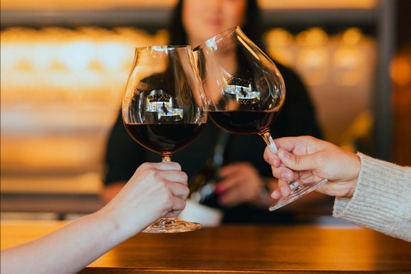 Two Riedel tulip wine glasses filled with Pinot Noir touching during a cheers.