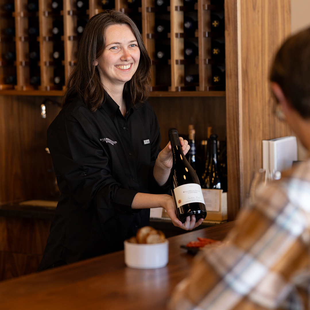 Willamette Valley Vineyards employee showcasing a bottle of wine to a guest.